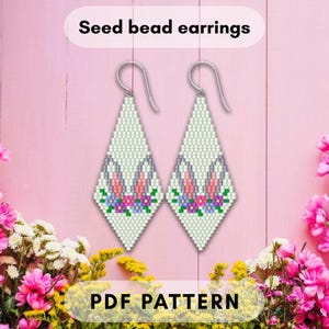 Peut inclure: Deux boucles d'oreilles en perles de rocaille en forme de losange, avec un fond vert clair et un motif de fleurs roses, violettes et bleues et une corne de licorne. Les boucles d'oreilles sont présentées sur un fond rose avec le texte "Seed bead earrings" et "PDF PATTERN".