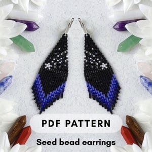 May include: Two beaded earrings with a black, blue, and white pattern. The earrings are triangular, with a fringe at the bottom. The image also includes the text "PDF PATTERN" and "Seed bead earrings".
