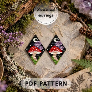 May include: Diamond-shaped seed bead earrings featuring a mushroom design with a red cap, white spots, and a beige stem against a black background with a crescent moon and purple accents. The earrings have gold-toned metal hooks for attachment.
