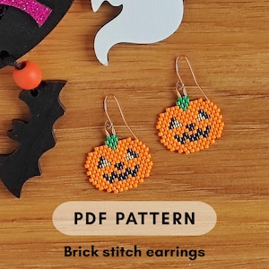 May include: Orange beaded pumpkin earrings with black facial features and green stems. The earrings are made with a brick stitch pattern and have gold-colored ear wires. The image also includes a wooden bat and ghost decoration. Text on the image says "PDF PATTERN" and "Brick stitch earrings."