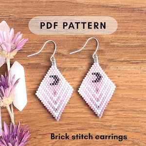 Könnte beinhalten: PDF-Muster für Ziegelstich-Ohrringe. Die Ohrringe sind rautenförmig mit einem Farbverlauf aus rosa und weißen Perlen. Jeder Ohrring hat ein schwarzes Halbmond-Design. Das Bild enthält den Text "PDF PATTERN" und "Brick stitch earrings".
