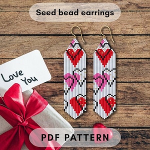 Puede incluir: Pendientes de cuentas de semillas con diseño de corazón. Los pendientes son blancos con corazones rojos y rosas. La imagen también incluye una caja de regalo con una cinta roja, una tarjeta que dice "Love You" y el texto "PDF PATTERN".