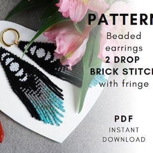 May include: A digital download pattern for beaded earrings. The earrings are black and white with a turquoise fringe. The pattern is for a 2 drop brick stitch with fringe.