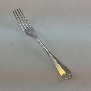 May include: A stainless steel fork with four tines and a teardrop-shaped handle. The fork is highly polished, reflecting light, and is designed for dining. The utensil is set against a neutral background.