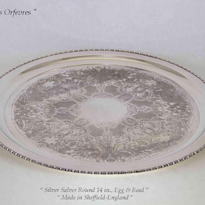 May include: A round silver salver, approximately 14 inches in diameter, with an egg and bead border. The salver features an ornate floral pattern in the center. The text "Guilde des Orfevres" and "Made in Sheffield-England" are visible.