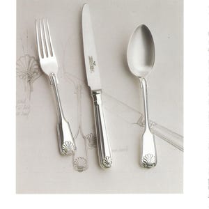 May include: Silverware set including a fork, knife, and spoon. The utensils have a Fiddle Thread & Shell design, with a shell motif at the base of each handle. The knife blade is silver and the handles are detailed. The text "FIDDLE THREAD & SHELL" is at the bottom.
