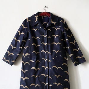 May include: A navy blue raincoat with a pattern of gold birds. The raincoat has a button-up front and two pockets.