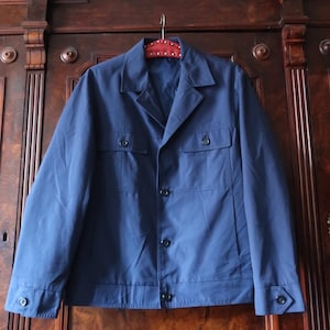 May include: A dark blue work jacket with a button-up front, two flap pockets, and a collar.
