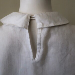 May include: White collared shirt with a keyhole opening in the back.