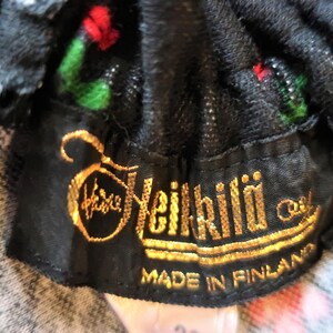 Może przedstawiać: Czarna metka z tkaniny ze złotym napisem "Heikkil&auml; Oy" i "Made in Finland".