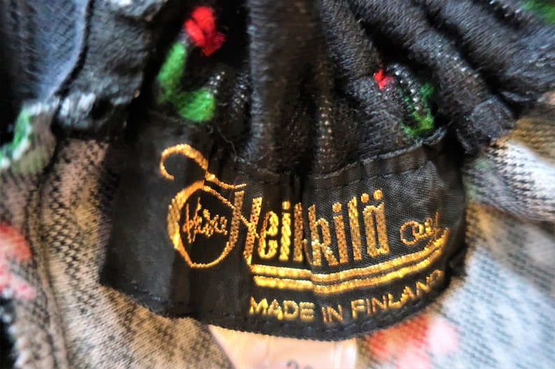Może przedstawiać: Czarna metka z tkaniny ze złotym napisem "Heikkil&auml; Oy" i "Made in Finland".