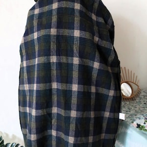 May include: A dark green, navy blue, and tan plaid jacket. The jacket has a hood and a dark green trim at the bottom. The plaid pattern is a classic design, suitable for fall or winter wear. The jacket is made of a soft, woven fabric.