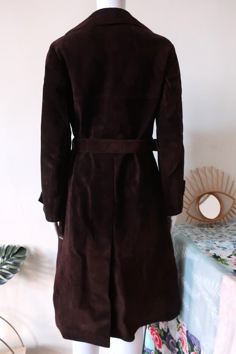 May include: A brown suede trench coat with a belt. The coat has a classic design and is perfect for fall or winter.