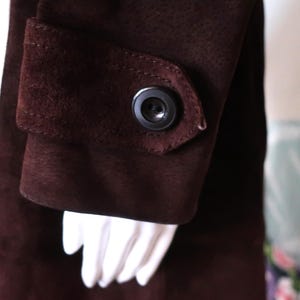 May include: A brown suede jacket with a button on the sleeve.