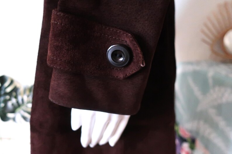 May include: A brown suede jacket with a button on the sleeve.