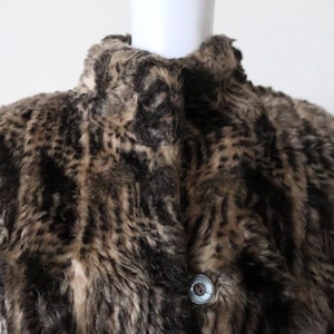 May include: A brown and beige faux fur coat with a leopard print pattern. The coat has a high collar and a button closure.