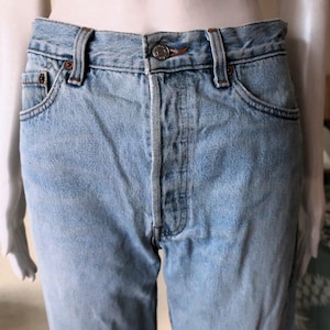 May include: Light blue denim jeans with a button fly and five pockets.