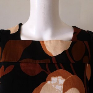May include: A black long-sleeved dress with a square neckline and a brown and beige abstract floral print.