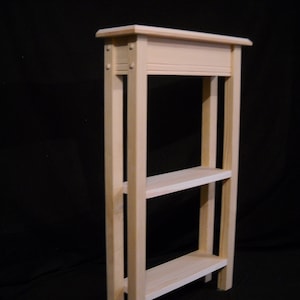 May include: A natural wood shelf unit with two shelves and a top rail. The shelf unit is made of unfinished wood and has a simple, modern design.