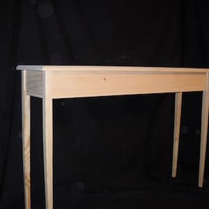May include: A simple, unfinished wooden console table with a rectangular top and four legs. The table is made of light-colored wood and has a natural finish.