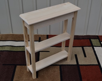 May include: A simple, unfinished wooden console table with two shelves. The table is made of pine wood and has a natural wood finish. It is 30 inches tall and 16 inches wide.