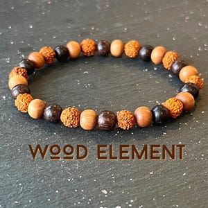 May include: A brown and black wooden beaded bracelet with the text "WOOD ELEMENT" below it.
