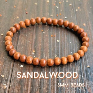 May include: A sandalwood bracelet with 6mm beads. The bracelet is made of natural wood and has a warm brown color.
