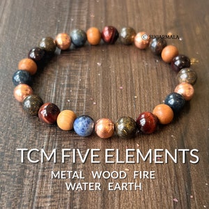 May include: A bracelet made of various gemstones and beads, representing the five elements of Traditional Chinese Medicine: Metal, Wood, Fire, Water, and Earth. The bracelet is brown, red, blue, and gold.