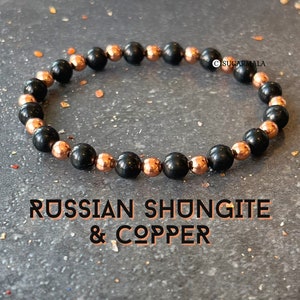 May include: A black and copper beaded bracelet with the text "RUSSIAN SHUNGITE & COPPER".