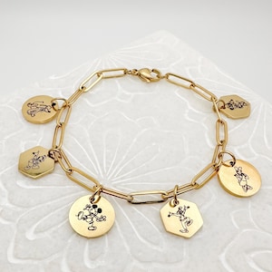 May include: A gold charm bracelet with six charms featuring different Disney characters. The charms are round and hexagonal in shape and have black and white illustrations of Mickey Mouse and other characters.