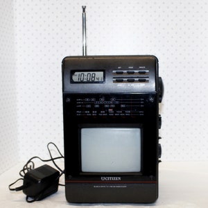 May include: A black and silver Citizen brand portable television and radio with a built-in clock displaying 10:08. The television is a black and white model with an antenna.