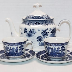 May include: A white and blue porcelain tea set featuring a teapot, two teacups, and saucers. The set has a classic blue and white Willow pattern design. The teapot has a lid and a curved spout. The teacups and saucers are round.