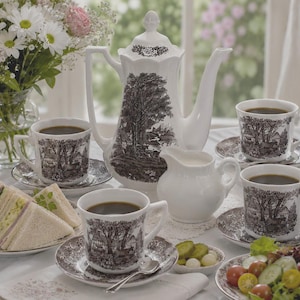 May include: A white porcelain tea set featuring a dark brown transferware landscape pattern. The set includes a tall teapot, a creamer, and three cups with matching saucers, all decorated with detailed illustrations of trees and rural buildings.