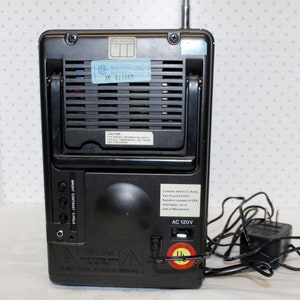 May include: Black and silver portable television with a built-in antenna, a power cord, and a label that reads "AC 120V".