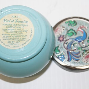 May include: A light blue Avon Bird of Paradise perfumed skin softener jar with a decorative lid. The lid features a peacock design with blue, green, pink, and white enamel. The jar contains 5 oz (142 cc) of product.