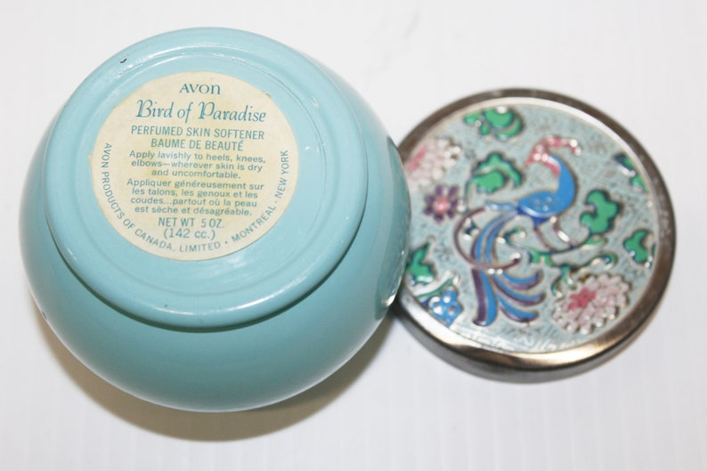 May include: A light blue Avon Bird of Paradise perfumed skin softener jar with a decorative lid. The lid features a peacock design with blue, green, pink, and white enamel. The jar contains 5 oz (142 cc) of product.