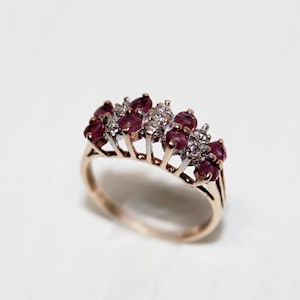 May include: A gold ring with a row of red rubies and white diamonds set in a prong setting.