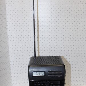 May include: A black and silver Citizen brand portable television with a built-in clock and radio. The television has a telescoping antenna and a small screen. The clock displays "10:11:43".