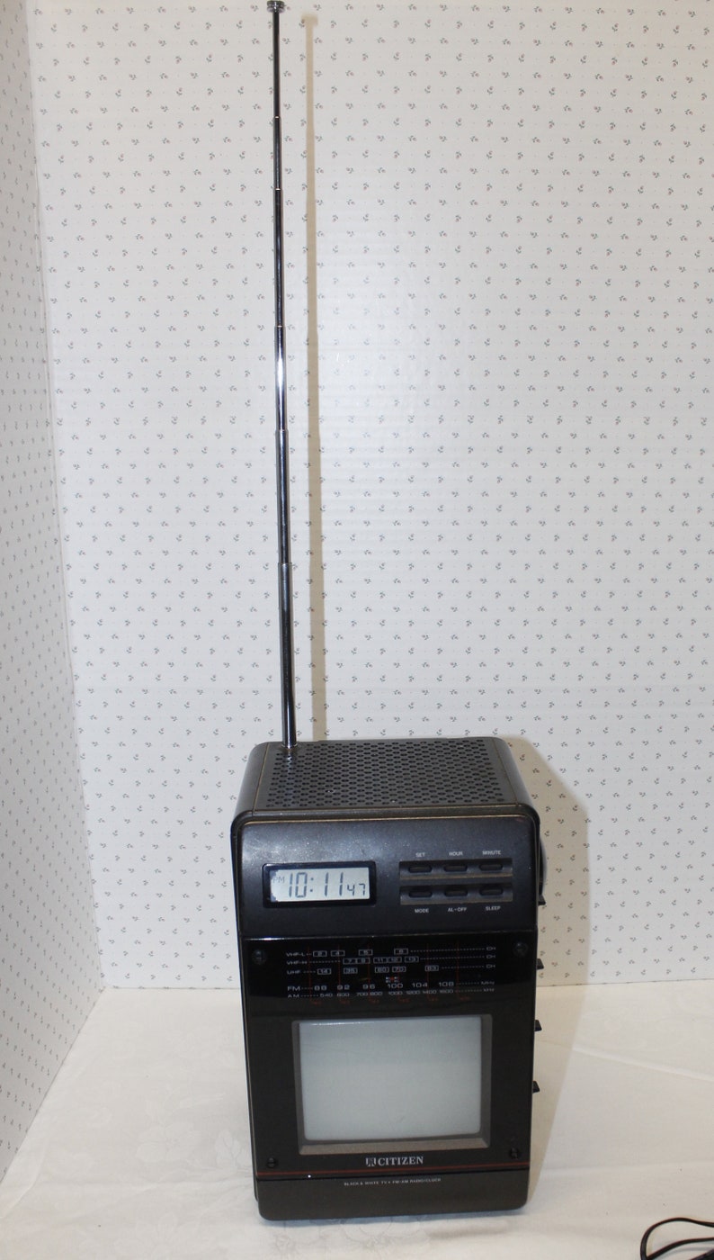 May include: A black and silver Citizen brand portable television with a built-in clock and radio. The television has a telescoping antenna and a small screen. The clock displays "10:11:43".