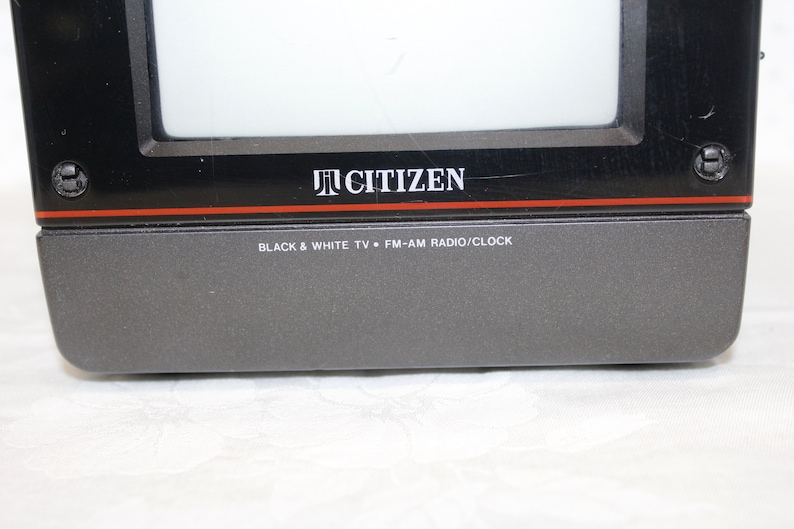 May include: A black and gray Citizen brand portable television with a black and white screen. The text "BLACK & WHITE TV * FM-AM RADIO/CLOCK" is printed on the front of the television.