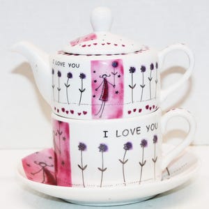May include: A white ceramic tea set with a teapot, teacup, and saucer. The set is decorated with a pink and white floral design, the words "I Love You", and a whimsical illustration of a person holding flowers.