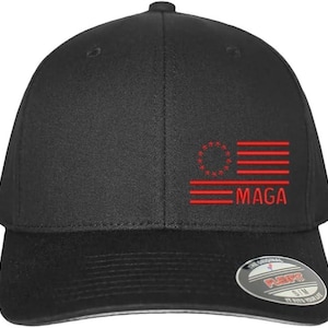 Puede incluir: Gorra de béisbol negra con una bandera estadounidense bordada en rojo con 13 estrellas en un círculo y el texto "MAGA".