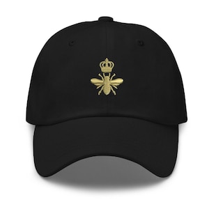 Peut inclure: Une casquette de baseball noire avec une abeille brodée en or portant une couronne.
