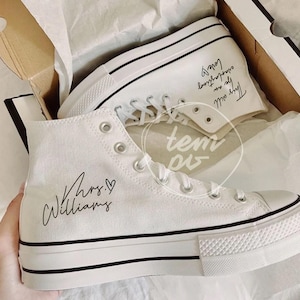 May include: White high-top sneakers with black trim and laces, presented in a box. The sneakers feature the text "Mrs. Williams" and "This will be an everlasting love" in black script. The shoes have a classic design.