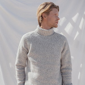 Puede incluir: Un su&eacute;ter gris de cuello alto con textura moteada. El su&eacute;ter tiene un cuello y pu&ntilde;os de canal&eacute;.