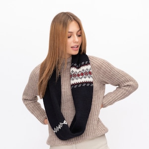 以下が含まれることがあります： ベージュのセーターを着て、ネイビーと白の模様のインフィニティスカーフをしている女性。