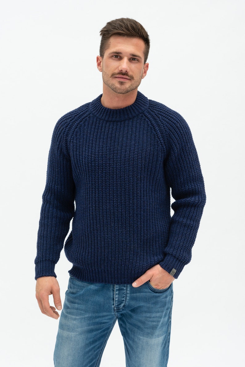 May include: A navy blue knitted sweater with a round neckline and long sleeves. The sweater has a ribbed texture.