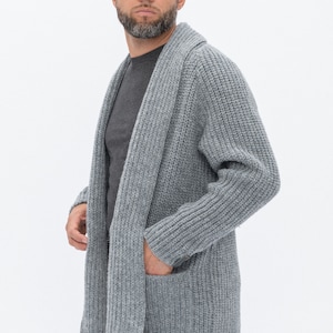 May include: A gray knitted cardigan with a shawl collar and a pocket on the front.