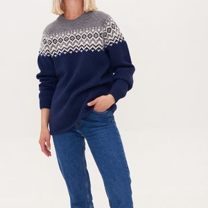 May include: A navy blue sweater with a grey and white geometric pattern around the neckline. The sweater is made of a soft, comfortable material and has a relaxed fit.
