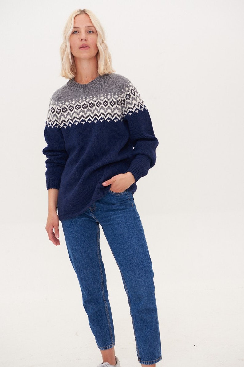 May include: A navy blue sweater with a grey and white geometric pattern around the neckline. The sweater is made of a soft, comfortable material and has a relaxed fit.